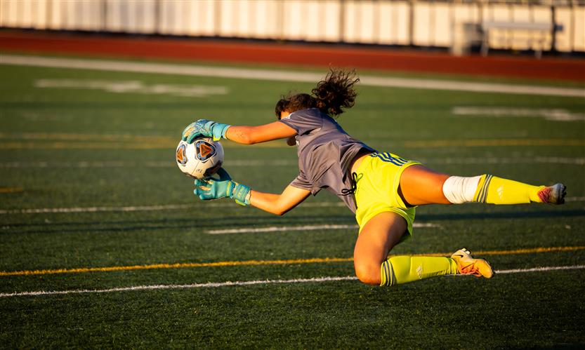 A goalkeeper dives to save the ball